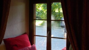 A room with a large window, a red pillow, and a wooden bench.