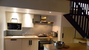 A modern kitchen with white cabinets, a microwave, stove, and a large bowl on the counter.