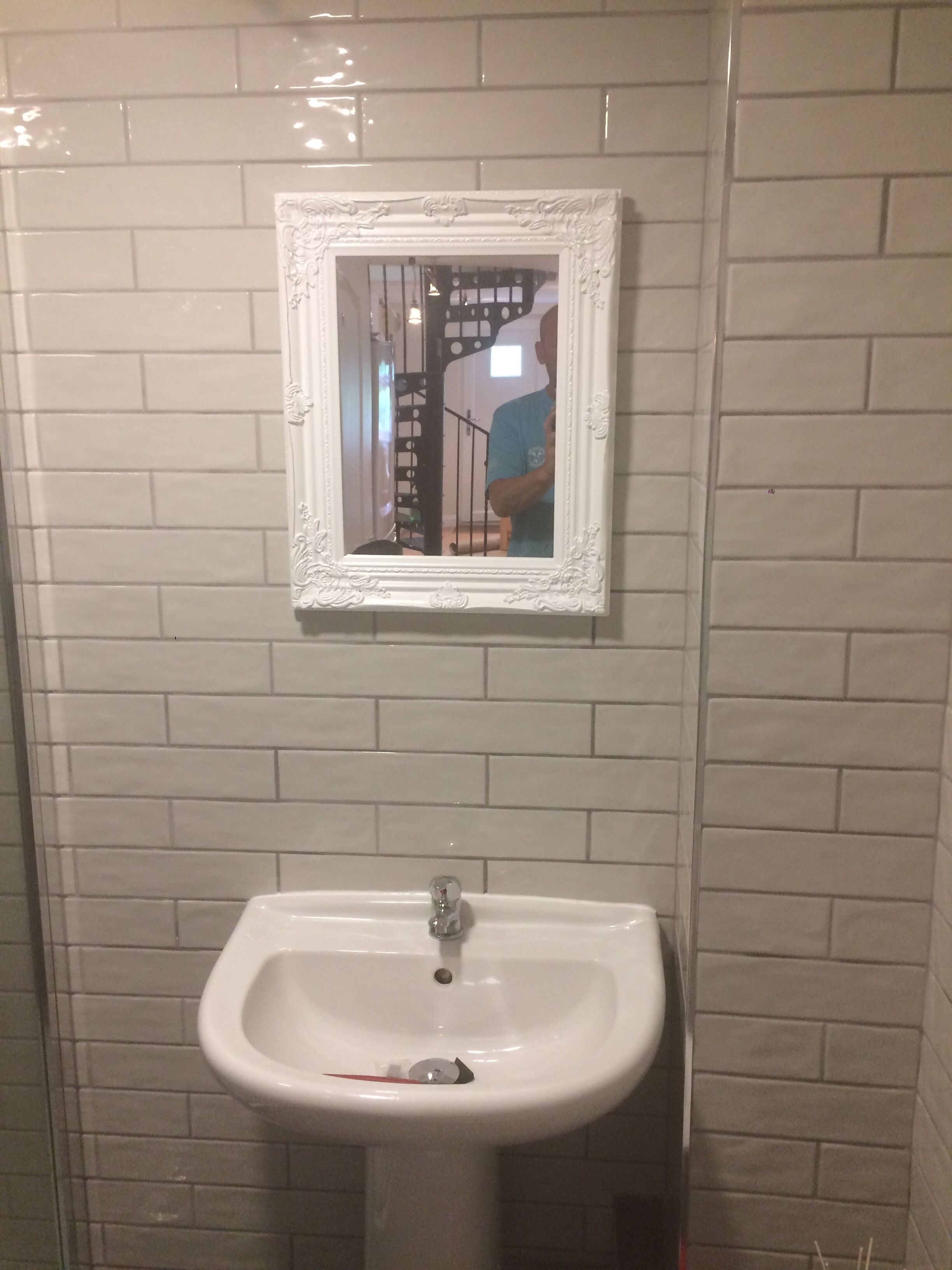 A bathroom with a white sink and a mirror with an ornate frame.