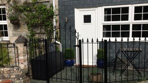 A stone house with a black metal gate, a white door, and a small window. - Cosy Cornish Bolt Hole, Pet Friendly (Truro)