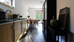 Eine moderne Küche mit Holzausstattung, einer schwarzen Arbeitsfläche und einem Essbereich mit Tisch und Stühlen.