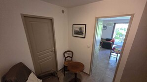 A hallway with a door, a chair, a small table, and a framed picture on the wall. - Countryside, garden on large plot, with dominant terrace and views (Lasalle)