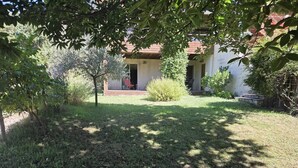 A residential property with a well-maintained lawn, a small patio area, and a house with a red roof. - Countryside, garden on large plot, with dominant terrace and views (Lasalle)