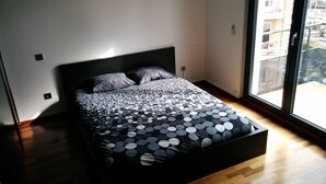 Camera da letto moderna con un ampio letto, una testata nera e vista sulla città attraverso una grande finestra.