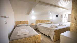 A room with two wooden bunk beds, a small wooden nightstand, and a white wall with a single light fixture. - Villa Barletta apartment mansarded in villa on the first floor number 5 (Marina di Acate)
