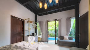 Une chambre avec un grand lit, un canapé, une porte en bois, une étagère et une vue sur une piscine.