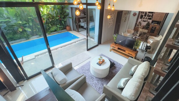 Un salon moderne avec vue sur la piscine, de grandes fenêtres et un téléviseur.