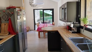 A modern kitchen with a dining area, a coffee machine, and a view of the outdoors.