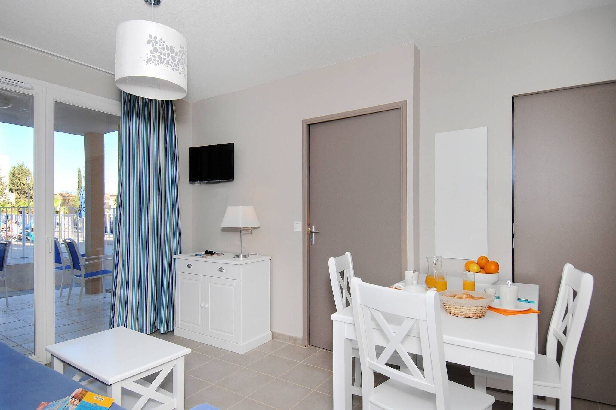 A hotel room with a dining table, chairs, a television, a cabinet, and a door.