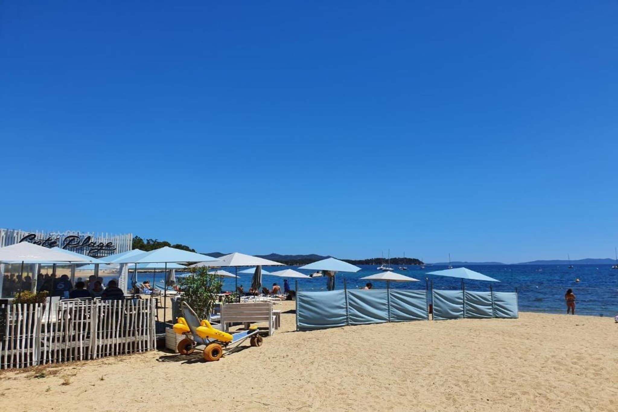 Een strand met parasols, ligbedden en een hek.