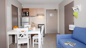 A compact kitchen with a microwave, refrigerator, and a small dining area with a table and chairs. - Apartment in France with Pool and Pine Views (La Londe les Maures)