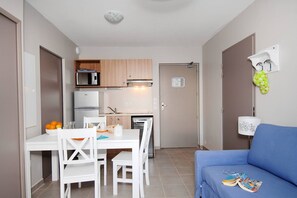 A compact kitchen with a microwave, refrigerator, and a small dining area with a table and chairs. - Apartment in France with Pool and Pine Views (La Londe les Maures)