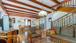A spacious living area with wooden beams, a sofa set, and a television.