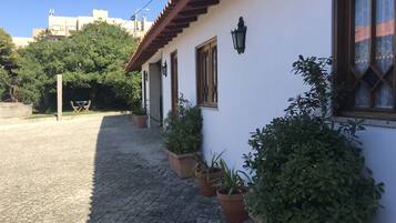 Traditional building with a charming facade, featuring windows with wooden frames and a door, surrounded by potted plants on a cobblestone street.