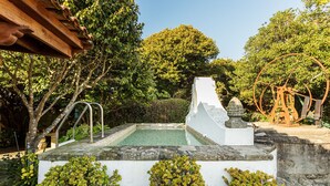 Ein Poolbereich mit einer weißen Struktur, Metalltreppen und Topfpflanzen.