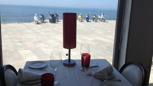 Ein Tisch für zwei mit Blick aufs Meer und darüber hinaus abgestellte Roller.