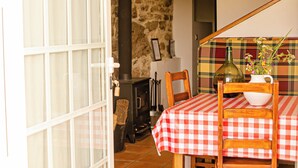 Una habitación acogedora con una mesa de cuadros, sillas de madera, una pared de piedra y una chimenea.