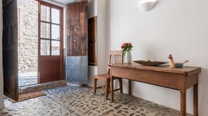 A rustic interior with a wooden door, a stone floor, and a table with a vase of flowers. - Ca S'angel (Soller)