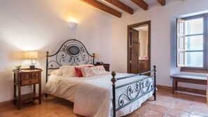 Un dormitorio con cama, mesitas de noche, lámpara, espejo y ventana.