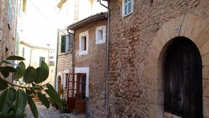 Una calle estrecha con edificios de piedra, una puerta de madera y una reja metálica.