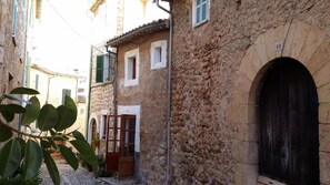 A narrow street with stone buildings, a wooden door, and a metal gate. - Ca S'angel (Soller)