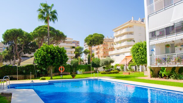 A swimming pool surrounded by greenery and multi-story buildings. - Modern apartment in Puerto marina (Benalmádena)