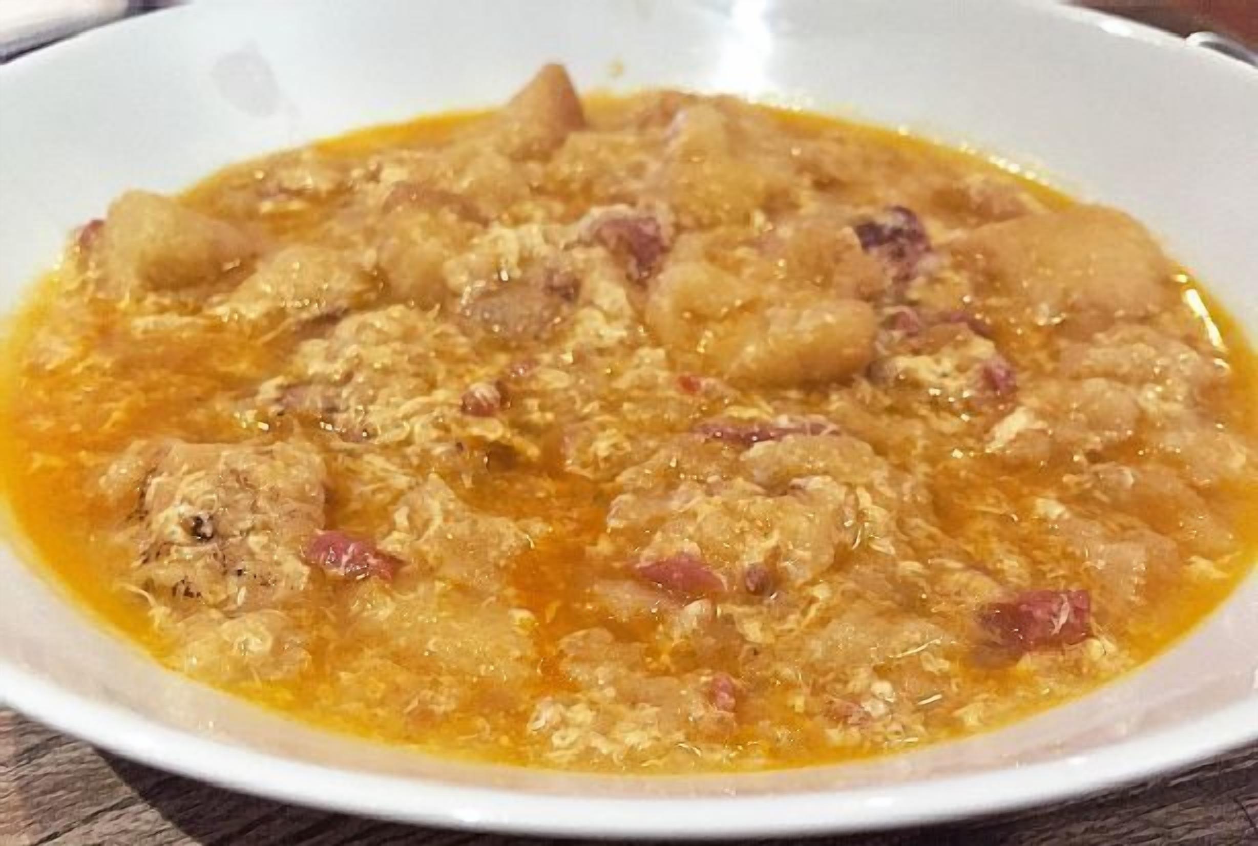 Eine Schüssel Suppe mit Fleisch- und Gemüsestücken in klarer Brühe.