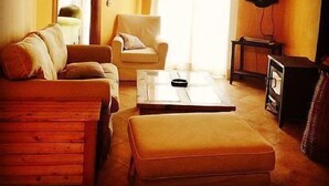 A living room with a sofa, armchair, ottoman, and a television on a stand. - Rural house (full rental) Rebollares II for 4-5 people (Piedralaves)