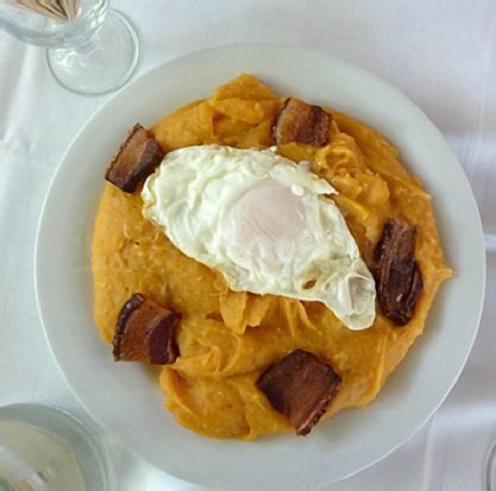 A plate of food with a fried egg, hash browns, and bacon.