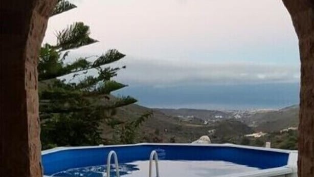 A balcony with a view of the sea, a blue pool, and a wicker chair. - VILLA HEMI, WITH DOUBLE ROOMS (Lomitos de Correa)