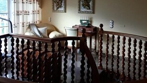 A spacious room with a large window, a chandelier, and a staircase with a wooden railing. - VILLA HEMI, WITH DOUBLE ROOMS (Lomitos de Correa)
