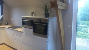 Una cocina moderna con armarios blancos, electrodomésticos de acero inoxidable y estructura de vigas de madera.