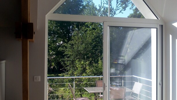 Un interior moderno con un amplio ventanal que da a una terraza exterior.