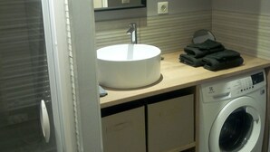 Un baño de hotel pequeño con lavabo, espejo y lavadora.
