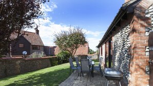 Un espace patio équipé d’un barbecue, de meubles de jardin et d’un mur en pierre.