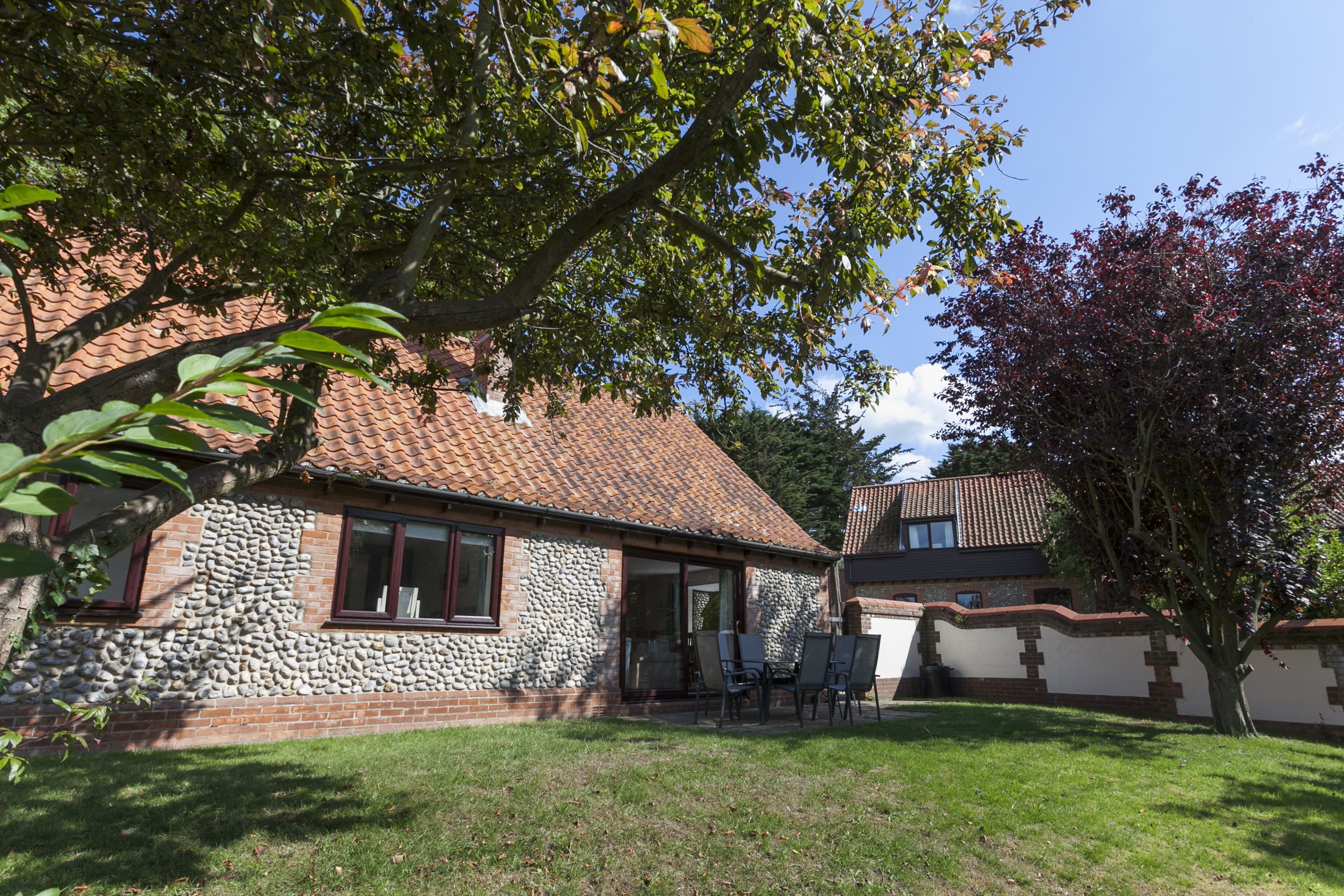 A house with a stone facade, a tiled roof, and a well-maintained lawn.