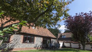 Une maison avec une façade en pierre, un toit en tuiles et une pelouse bien entretenue.