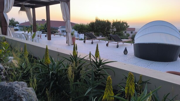 Eine Dachterrasse mit Liegestühlen, einer Pergola und einer Kuppelkonstruktion.