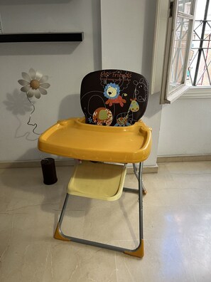 A high chair with a yellow tray and a black seat with animal designs.