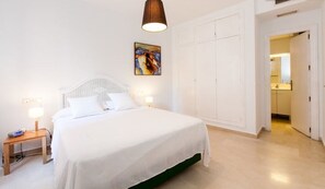 Un dormitorio con cama, mesitas de noche, un armario y un cuadro en la pared.