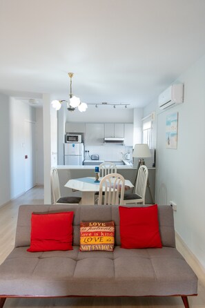 Une cuisine moderne avec des meubles blancs, un four à micro-ondes et un coin repas comprenant une table et des chaises.