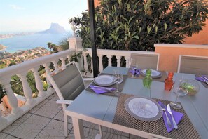 Mesa posta para dois em uma varanda com vista para o oceano e uma montanha ao longe.