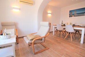 A modern dining area with a wooden table, white chairs, and a white sofa. - MARYVILLA0831-Gran Vista-Wifi y Parking Gratis. (Calpe)