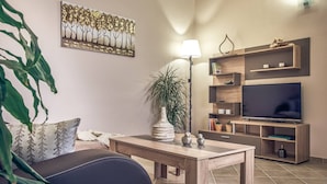 A modern living room with a flat-screen TV, wooden shelves, a coffee table, and a potted plant. - CORAL  VILLA with private pool at 100 m from the sea (Zante (Zacinto))
