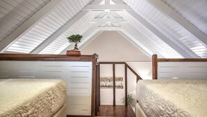 A loft bedroom with a sloped ceiling, two beds, a wooden staircase, and a potted plant. - CORAL  VILLA with private pool at 100 m from the sea (Zante (Zacinto))