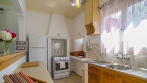 A kitchen with a white refrigerator, oven, and sink. There is a wooden countertop and a basket of rolled towels. A sign with the words "Live Laugh Love" is visible. - Perfect for families or couples looking for privacy (Paxos)