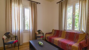 A room with a sofa, two chairs, a table, and curtains. - Perfect for families or couples looking for privacy (Paxos)
