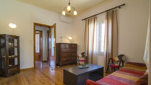 A room with a wooden floor, a bed with a striped blanket, a desk with a lamp, a dresser, and a chair. - Perfect for families or couples looking for privacy (Paxos)