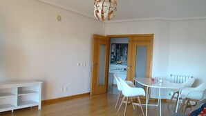 Ein modernes Wohnzimmer mit Essbereich, Holzboden, einem weißen Sofa, einem weißen Tisch und einer außergewöhnlichen, kugelförmigen Leuchte.