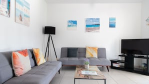 Un salon moderne avec un canapé gris, une table basse, un lampadaire et un téléviseur à écran plat.
